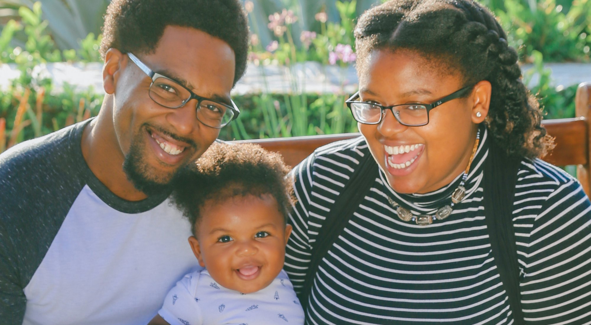 A mother and father laughing with their baby